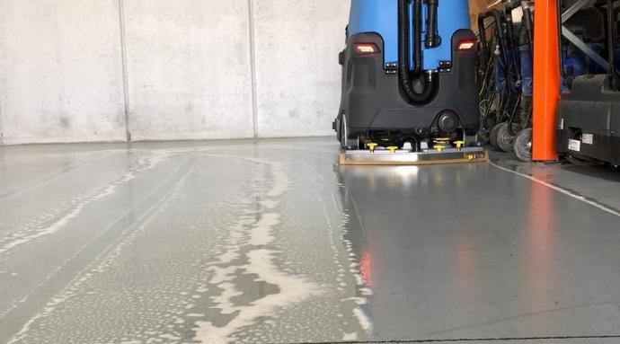 Degreaser industrial cleaner on floor being cleaned by scrubbing machine