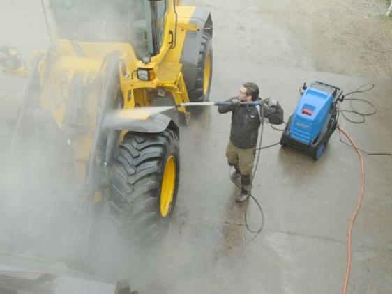 Industrial cleaning machine removing dust buildup around a loader at a mining facility.